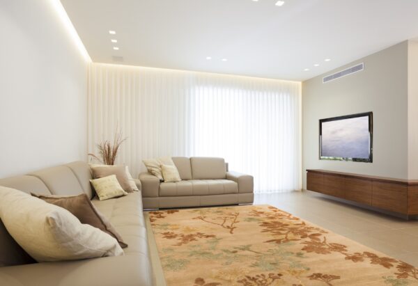 Tan floral rug with rust and gold botanicals on light tiled floor under modern beige sectional seating.