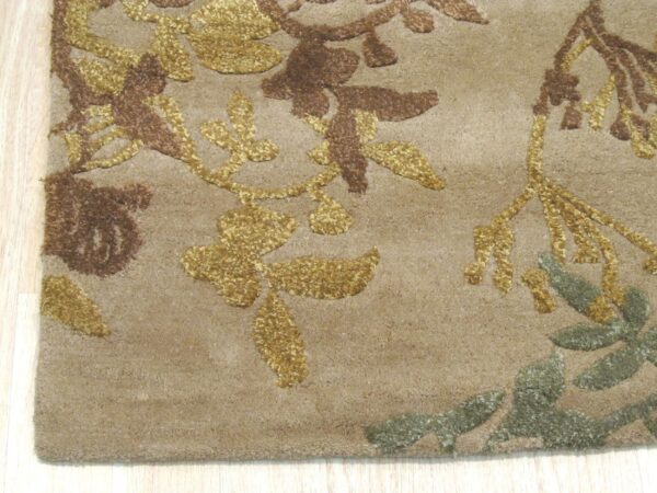 Textured tan rug featuring raised gold, brown, and sage floral patterns on a light wooden floor.