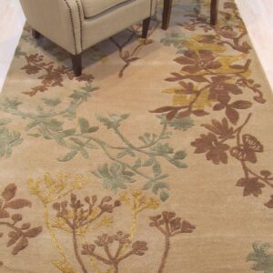 Tan rug with raised brown, gold, and sage floral patterns beneath an armchair on a light wood floor.
