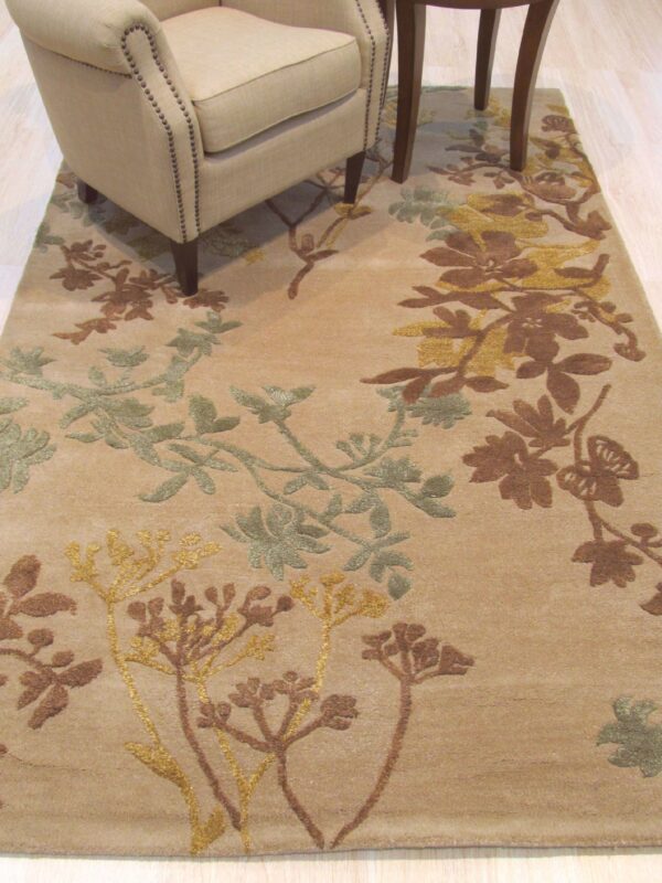 Tan rug with raised brown, gold, and sage floral patterns beneath an armchair on a light wood floor.