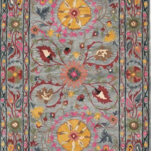 Dusty blue rug with ornate floral patterns in yellow, pink, burgundy, and deep blue borders.