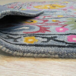 Medium pile blue rug edge, featuring pink, yellow, and green floral motifs, displayed on light wood floor.