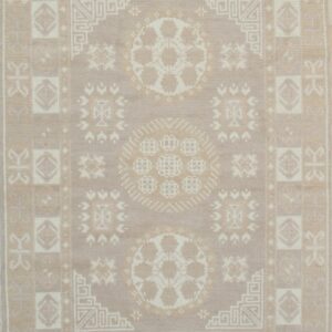 A muted taupe and off-white rug with a geometric tribal pattern and central medallions.