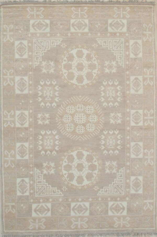 A muted taupe and off-white rug with a geometric tribal pattern and central medallions.