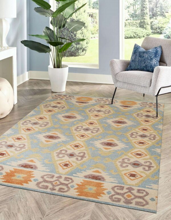 A geometric low-pile rug in blue, cream, and orange accents a room with a gray chair and window.