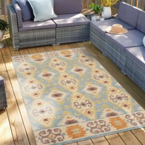 Geometric outdoor rug in shades of blue, cream, and rust accenting a grey patio sectional on a wood deck.