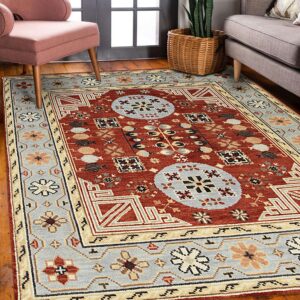 Terracotta and blue-gray geometric rug on wood floors between a pink chair and a gray sofa.