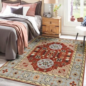 Geometric red, blue, and beige rug placed on gray wood floor beside a bed and nightstand.