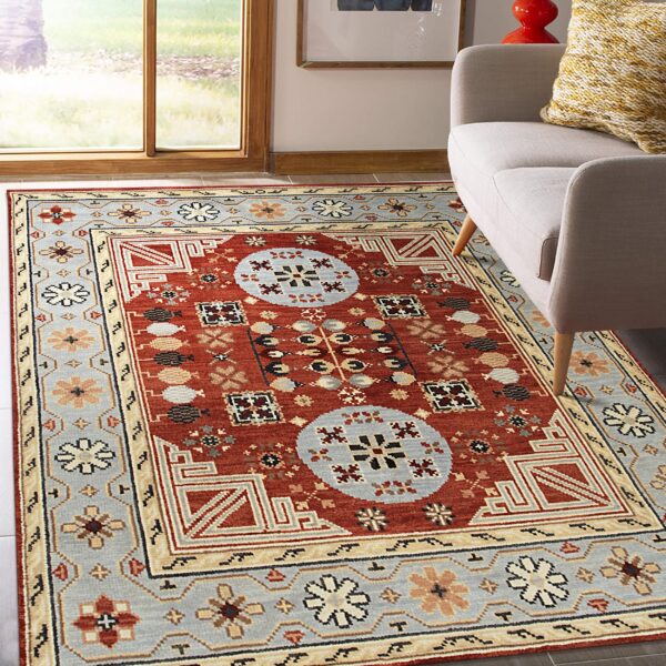 Rust red and blue-gray traditional geometric rug on dark flooring next to a light gray upholstered chair.