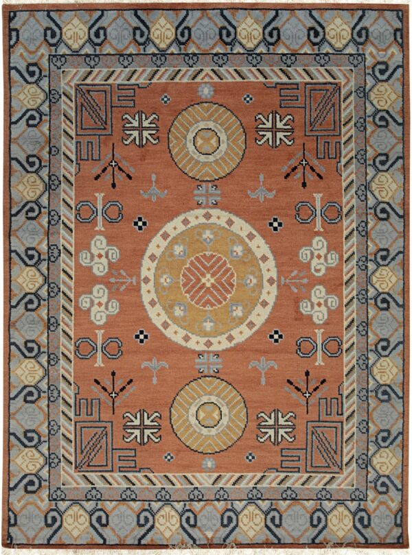 Rust orange rug with gold, gray, and dark blue geometric tribal symbols and medallions.