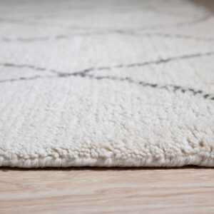 High-pile cream rug with faint gray geometric lines rests on light wood flooring.