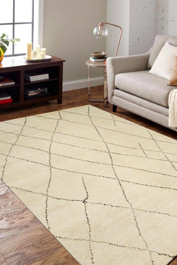 Off-white rug with a thin, irregular dark diamond pattern laid on wood flooring near a gray armchair.