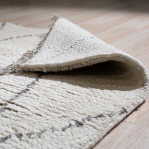 The high-pile cream rug with a gray lattice pattern is rolled back on light wood floors.