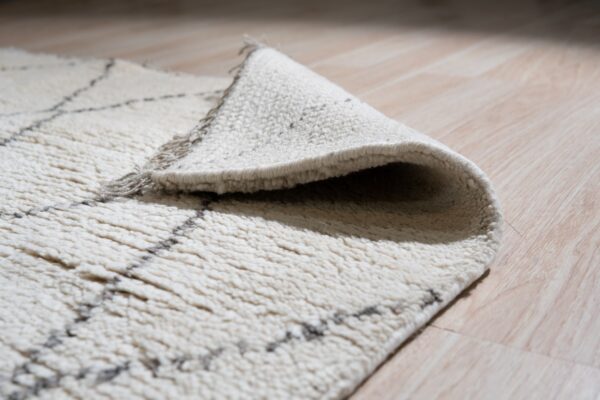 The high-pile cream rug with a gray lattice pattern is rolled back on light wood floors.