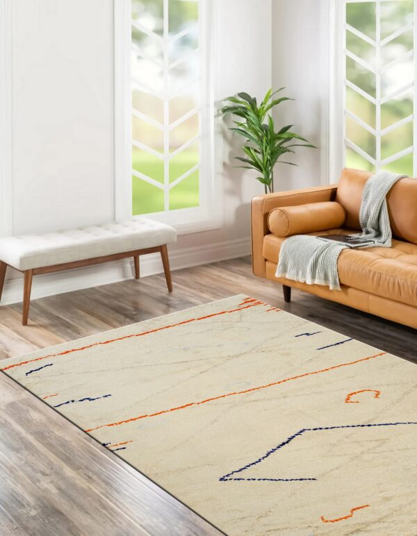 Cream textured rug with scattered orange and navy blue abstract marks in a bright living room.