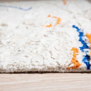 A shaggy cream rug with high pile displays abstract blue and orange patterns on light wood flooring.