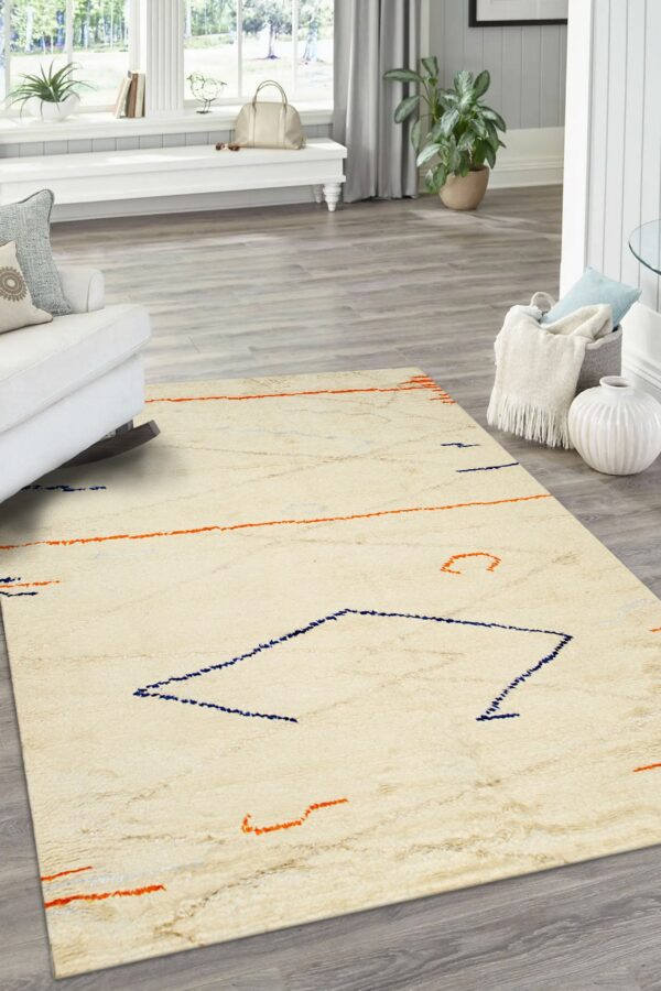 Textured cream rug with sparse abstract navy and orange patterns on light gray wood flooring.