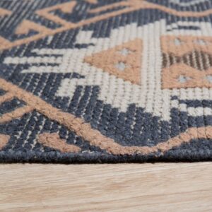 A close-up of a multi-textured geometric rug in dark gray, cream, and raised beige resting on wood flooring.