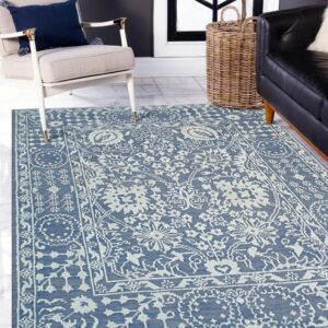 Blue flatweave rug with light floral patterns sits on white tiled flooring next to cream and black seating.