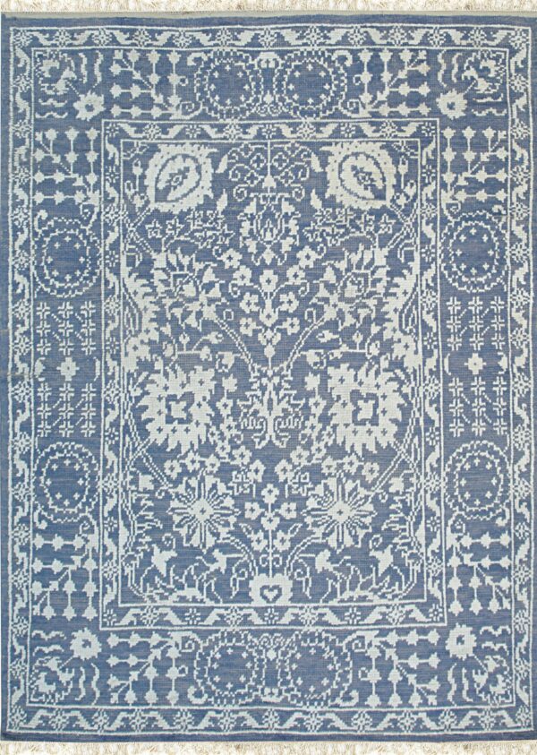 A detailed blue rug featuring an intricate light gray, low-pile floral medallion design and decorative borders.