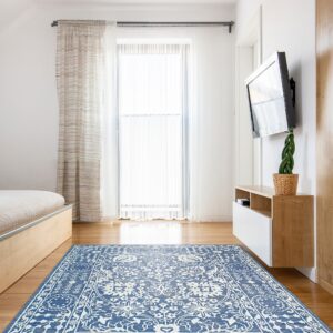 Blue and white ornate rug lies on a hardwood floor in a brightly lit room with white walls.
