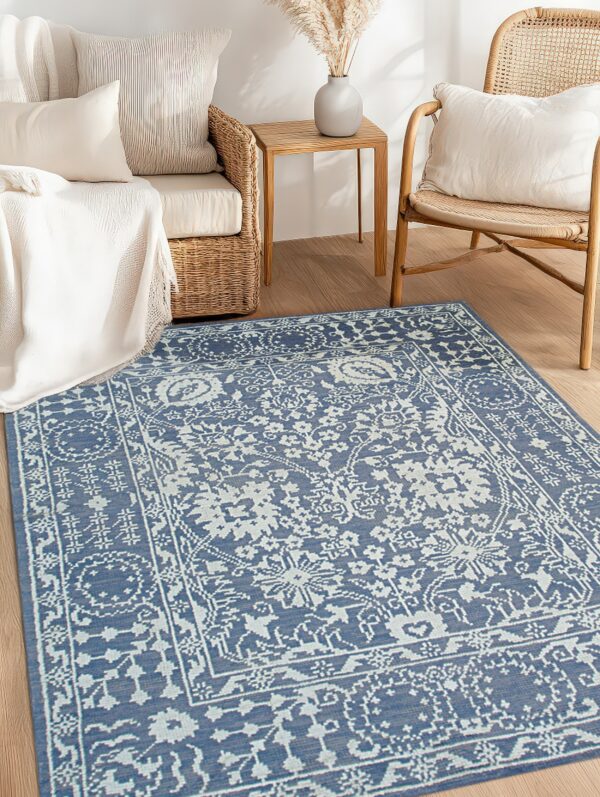 A blue and white traditional patterned rug on hardwood floors, framed by wicker furniture and a small wooden side table.