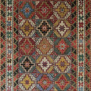 Geometric high-pile rug displaying stepped medallions in red, teal, gold, and cream squares.
