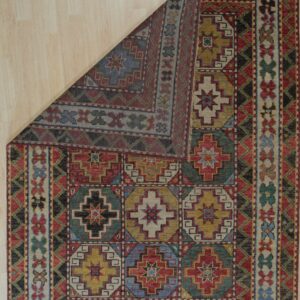 Geometric rug featuring a multi-colored medallion pattern, folded back on a light wood floor.