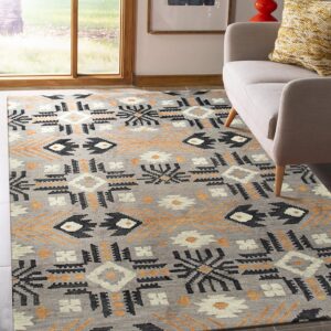 Geometric gray rug featuring black, orange, and white motifs sits under a light gray sofa by a sunlit window.