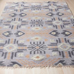 High-pile lavender rug with charcoal, cream, and apricot geometric motifs on light wood floor.
