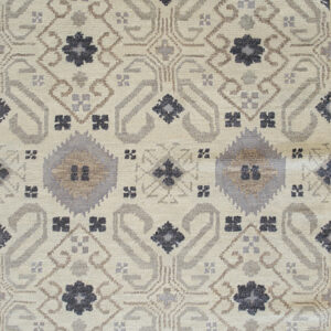 Textured cream rug with ornate repeating geometric medallions in shades of gray and brown, featuring short fringe.