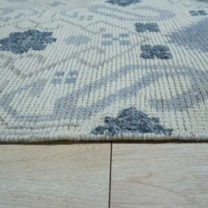 Close-up of a textured cream rug with high-low blue and gray geometric patterns on wood flooring.