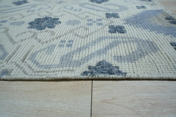 Close-up of a textured cream rug with high-low blue and gray geometric patterns on wood flooring.