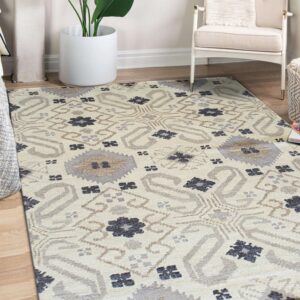 Neutral rug with gray, cream, and dark blue geometric patterns on wood floors beside a white chair and plant.