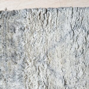 Shaggy, high-pile rug with mottled gray and off-white texture rests on light wood planks.