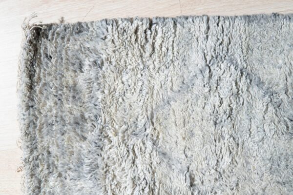 Shaggy, high-pile rug with mottled gray and off-white texture rests on light wood planks.