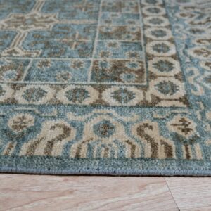 Teal, tan, and brown geometric rug detail resting on light natural wood plank flooring.