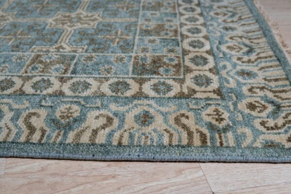 Teal, tan, and brown geometric rug detail resting on light natural wood plank flooring.