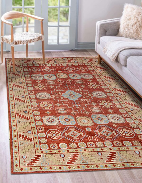 Red and beige traditional rug with blue geometric patterns sits on wood floors near a sofa.