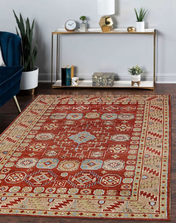 Terracotta rug with tan and light blue traditional motifs anchors a room with dark wood floors.