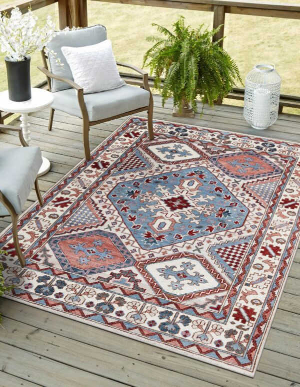 Blue, rust, and off-white geometric rug placed on a wooden deck with outdoor furniture and plants.