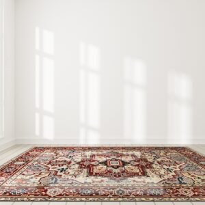 A traditional medallion rug in red, cream, and blue lies on light wood floors in a bright white room.
