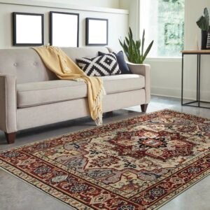 Traditional red, cream, and blue patterned rug displayed under a beige sofa on a modern concrete floor.