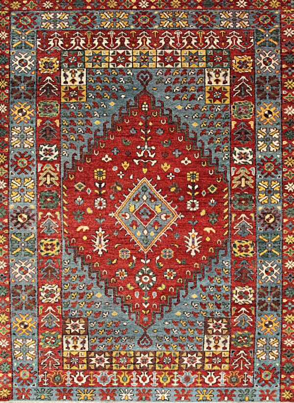 Traditional rug with a red central field and geometric borders in blue, yellow, and white.