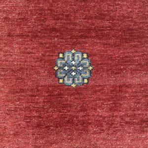 Textured burgundy rug with repeating geometric medallions in blue, cream, and yellow.