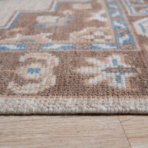 Textured pile rug in brown, cream, and blue geometric patterns shown near light wood flooring.