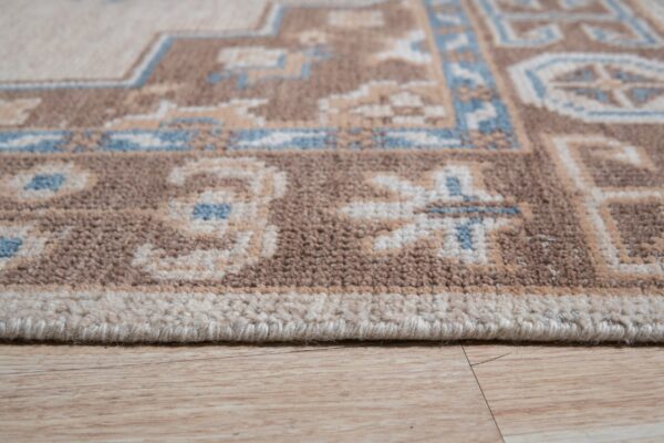 Textured pile rug in brown, cream, and blue geometric patterns shown near light wood flooring.