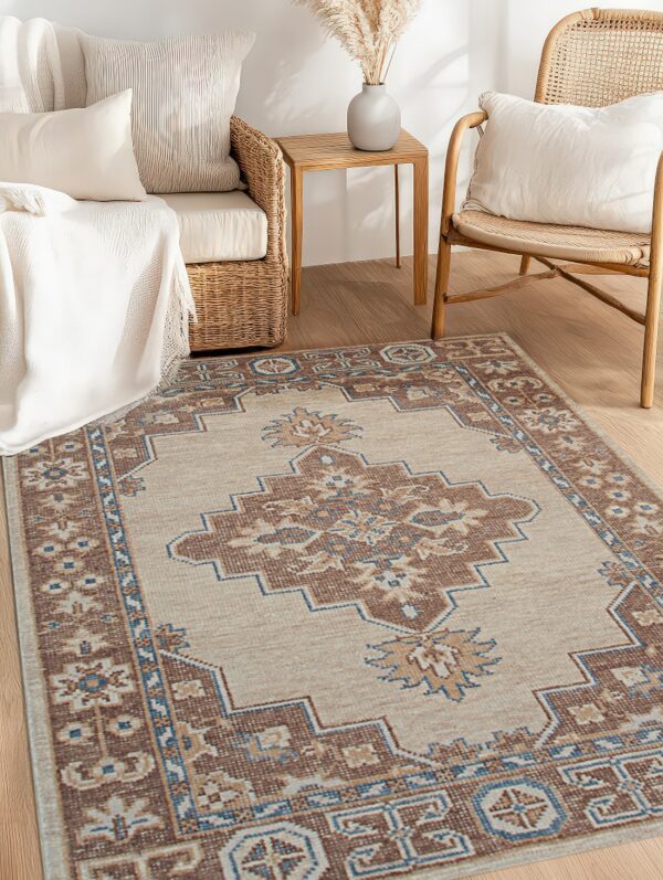 A beige rug with a brown and blue geometric pattern rests between rattan furniture on wood flooring.