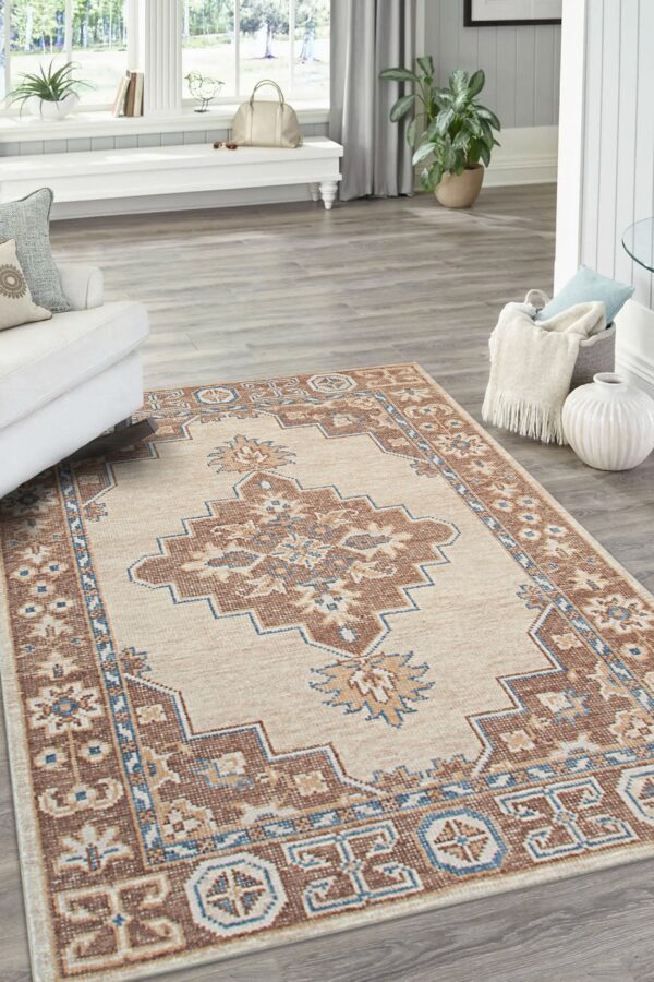 A cream and rust traditional patterned rug with blue accents rests on gray wood floors.
