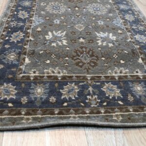 Charcoal gray medium pile rug with traditional blue, brown, and cream floral designs on light wood flooring.